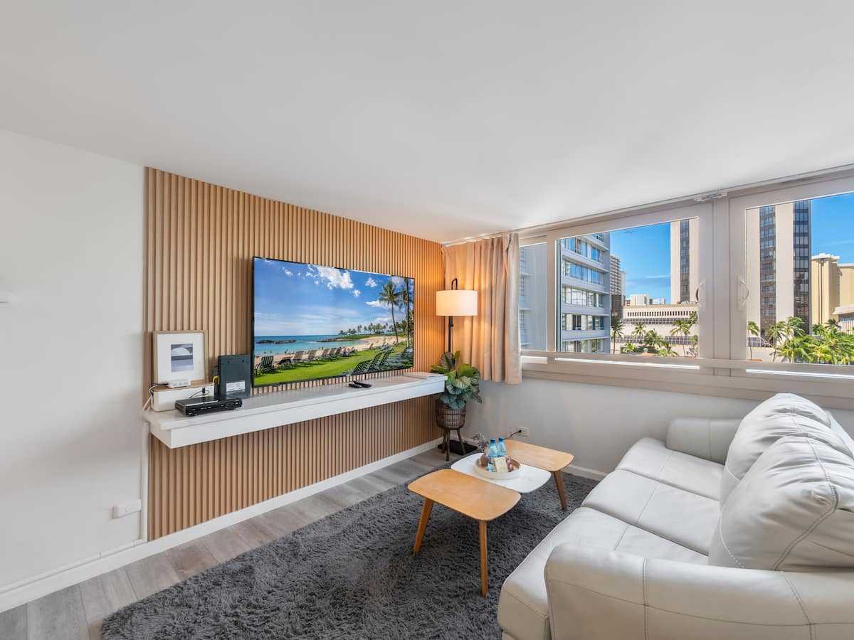 Living room with sleeper sofa, dining table, television, and corner windows