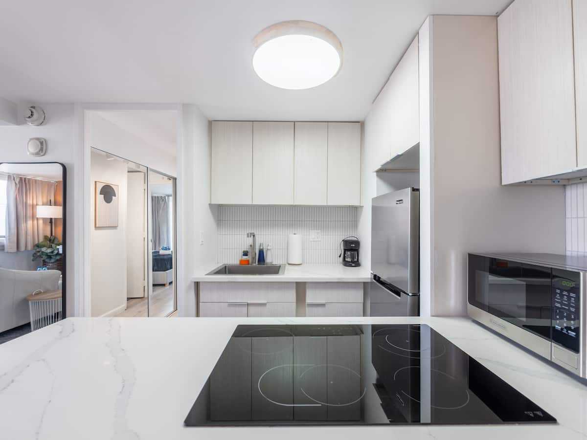 Kitchen cooktop, sink, microwave, and white cabinets